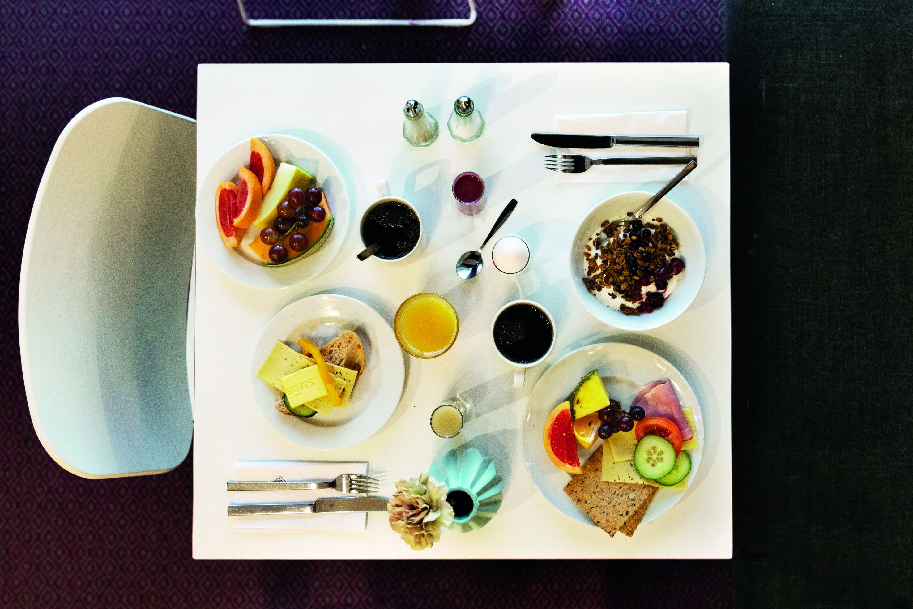 A breakfast table with various dishes, including fruits, bread, and beverages.