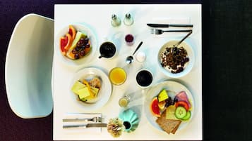 A breakfast table with various dishes, including fruits, bread, and beverages.