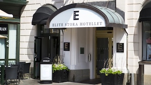 The exterior of the Elite Stora Hotellet with a prominent entrance, a flag, and potted plants. - Elite Stora Hotellet Linköping (Linkoping)