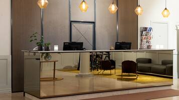 A reception area with a glass partition, two Lenovo computers, a plant, and a magazine rack.