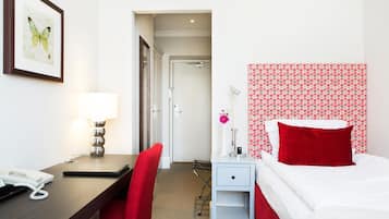 Habitación de hotel con escritorio, silla, cama y una obra de arte con una mariposa enmarcada.