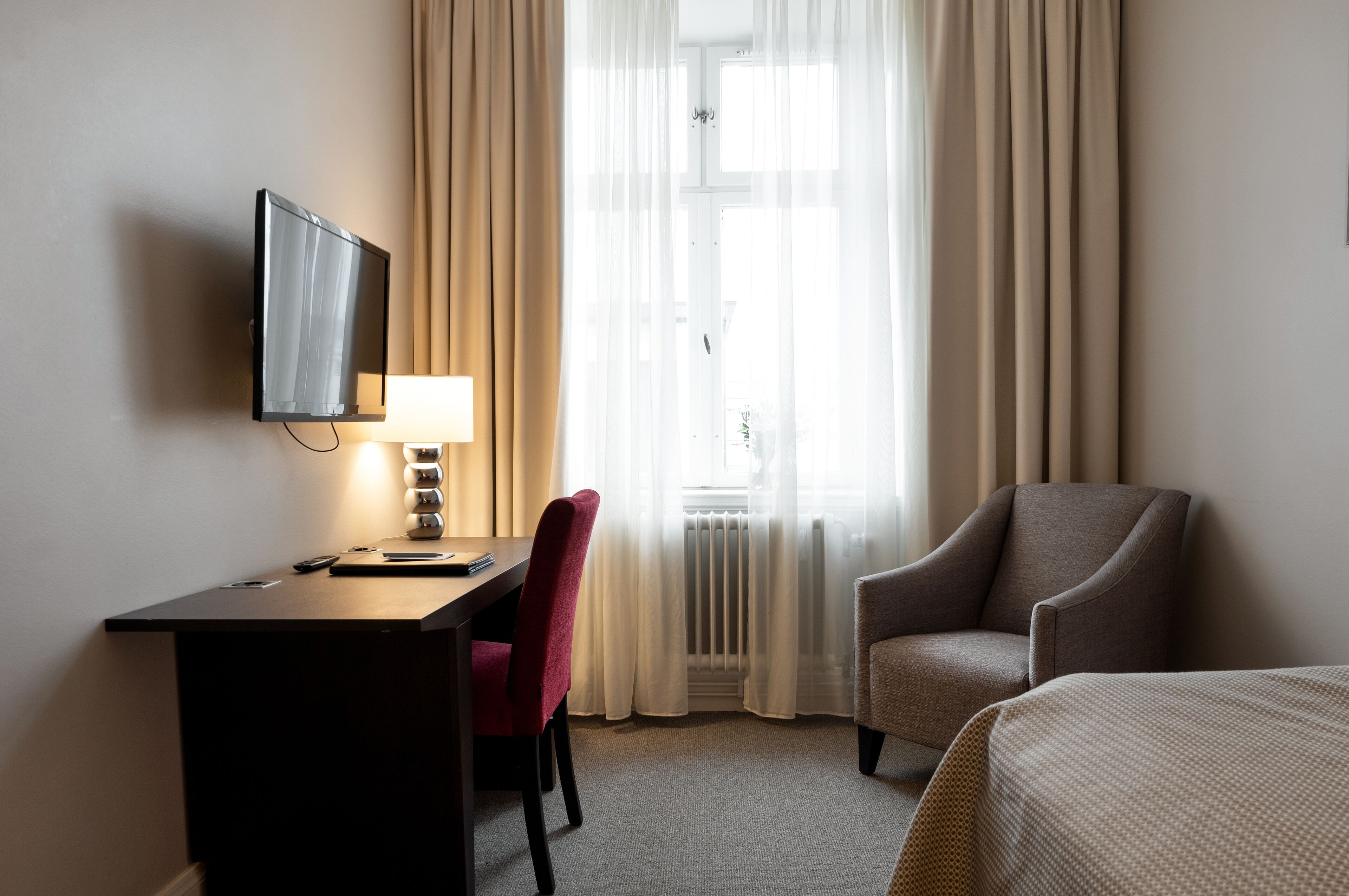 Habitació d'hotel amb escriptori, cadira, televisió i dos llits.