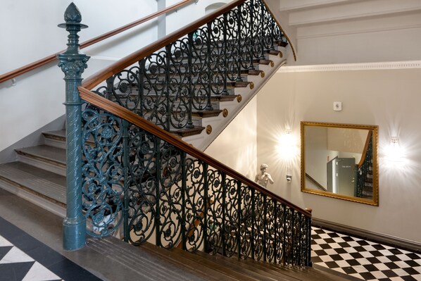A staircase with ornate black metal railings and a blue balustrade. - Elite Stora Hotellet Linköping (Linkoping)