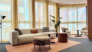 Un salon moderne avec un canapé, un pouf, une table basse ronde et des fauteuils.