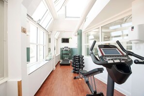 A modern gym with exercise equipment, large windows, and a wooden floor. - Hotel Kung Carl, WorldHotels Crafted (Stockholm)