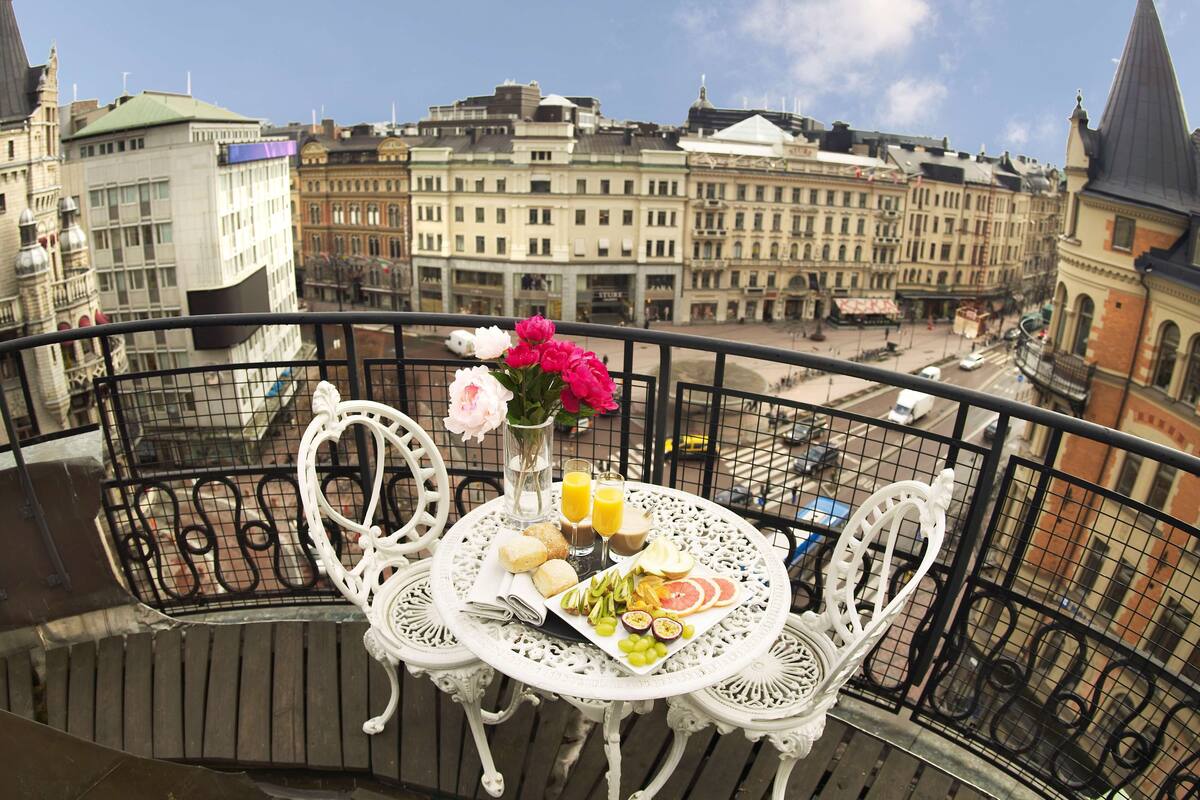 A balcony with a table set for breakfast, overlooking a cityscape with historic buildings.