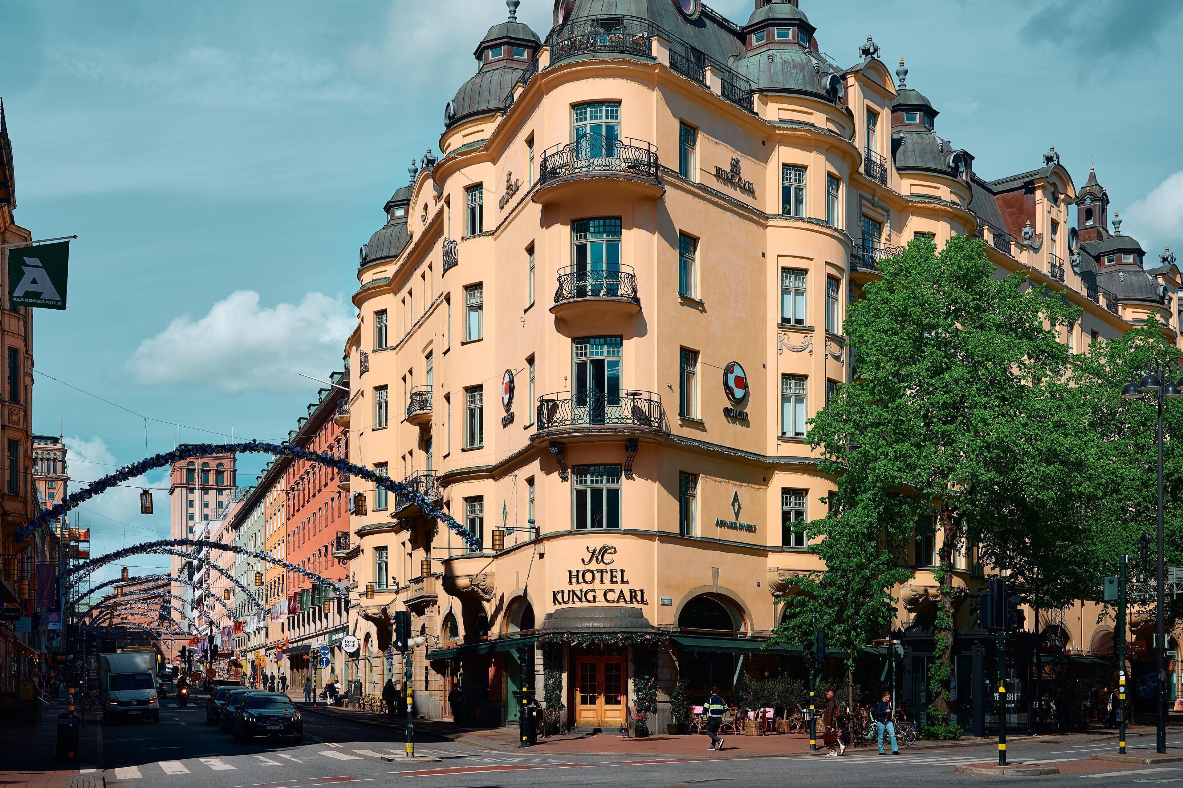 A historic building with a prominent entrance, multiple balconies, and a sign indicating it is a hotel.