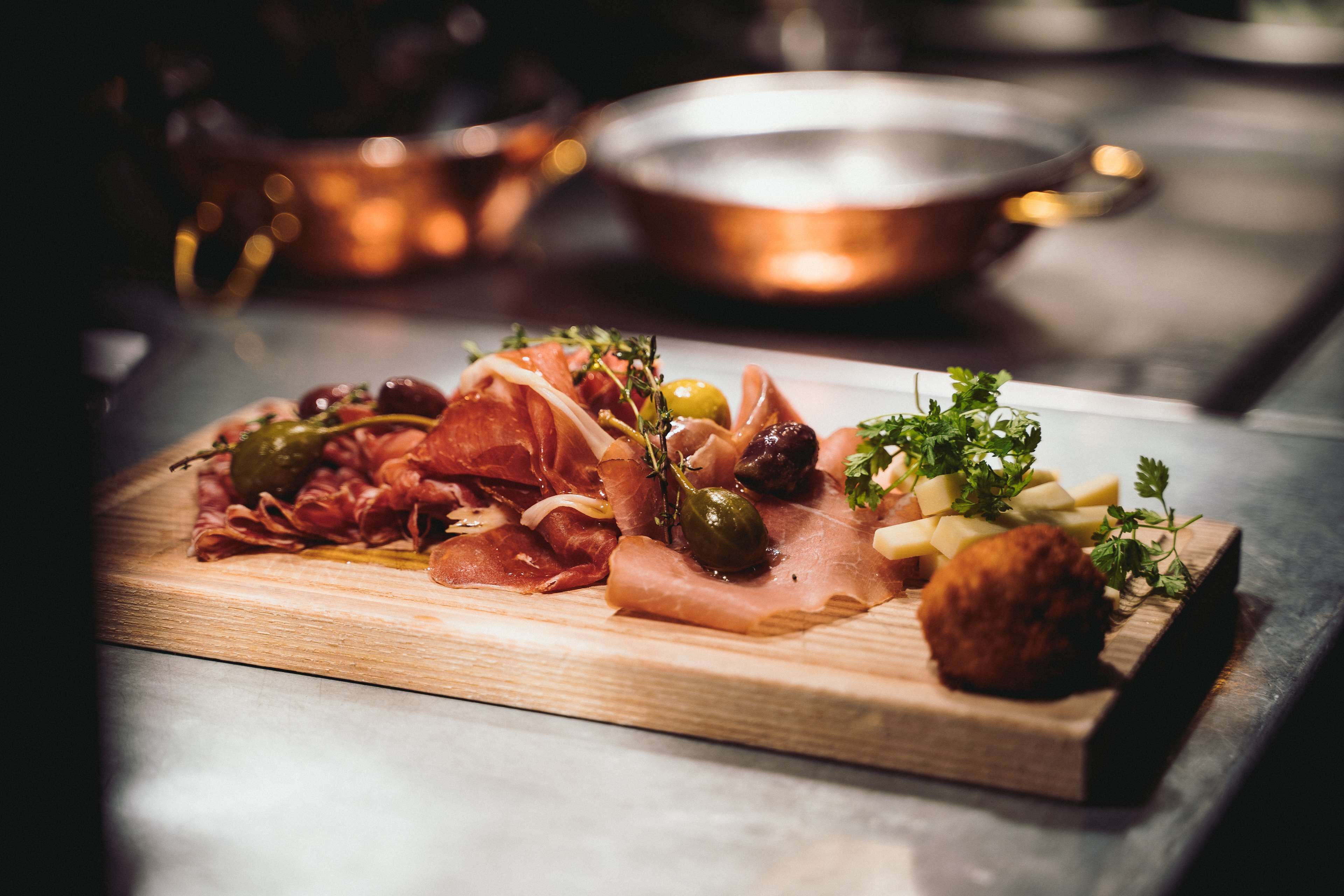 A wooden board with various meats and garnishes.