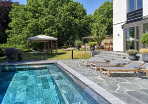 Una piscina al aire libre, sillones reclinables de piscina