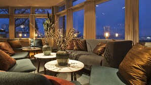 A cozy seating area with a sofa, armchairs, and a small table with candles and a vase of flowers. - Villa Lovik (Lidingo)