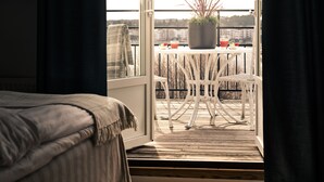 Un balcon avec une table et des chaises blanches, une plante en pot et un verre rempli de boisson.