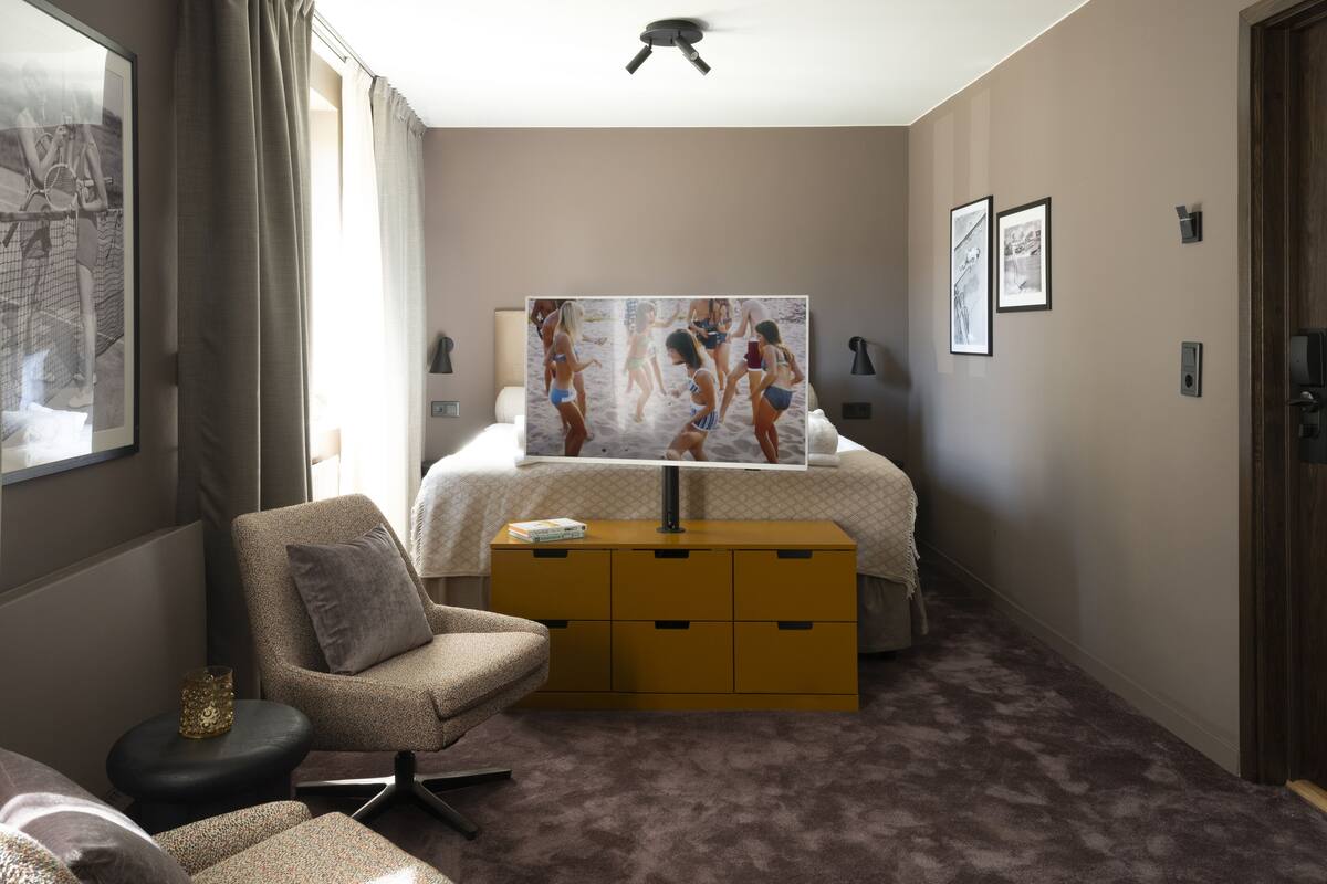 A hotel room with a bed, a sofa, a small table, a TV, and a dresser.