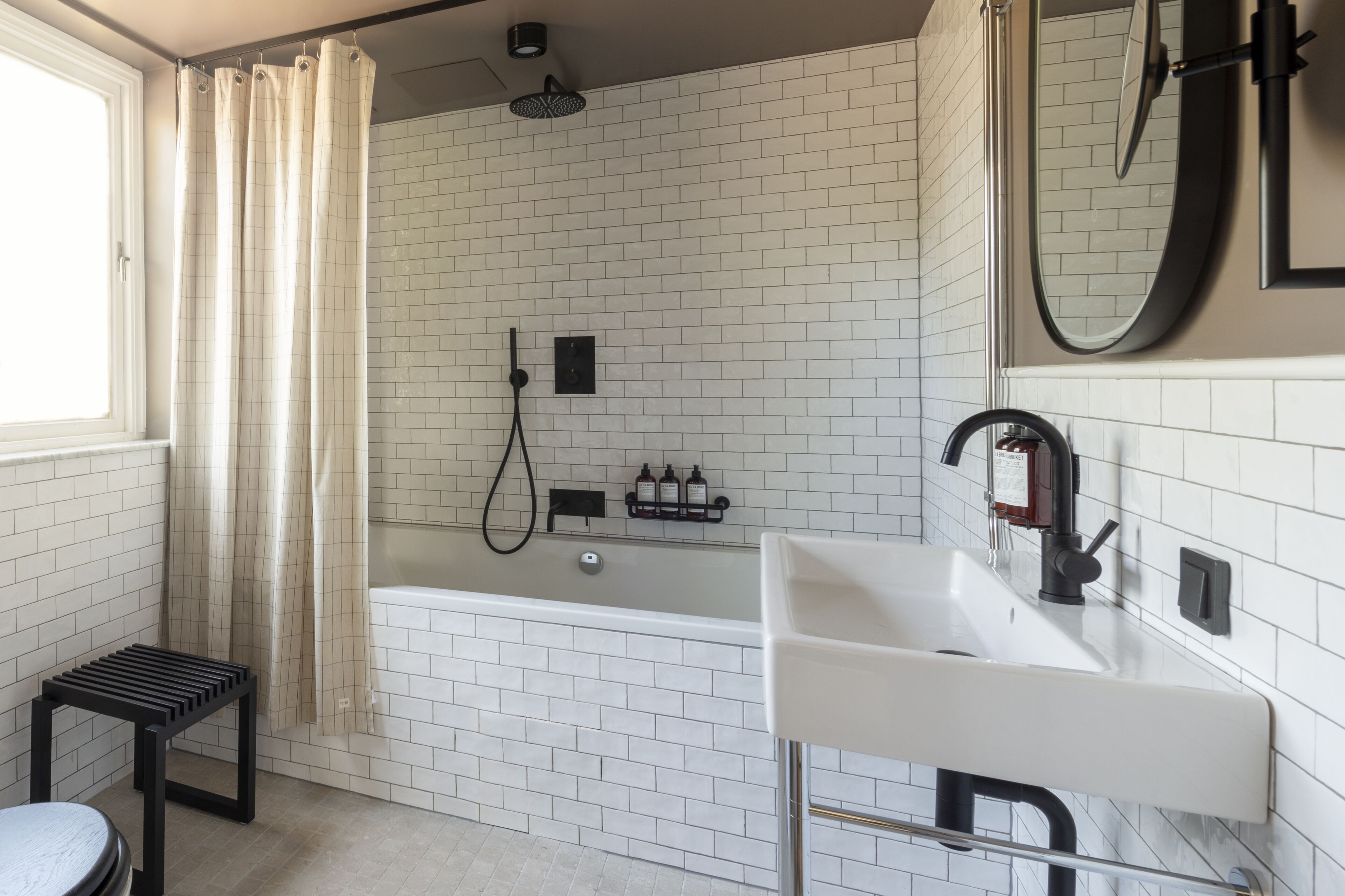 A modern bathroom with a white bathtub, a sink, and a shower.