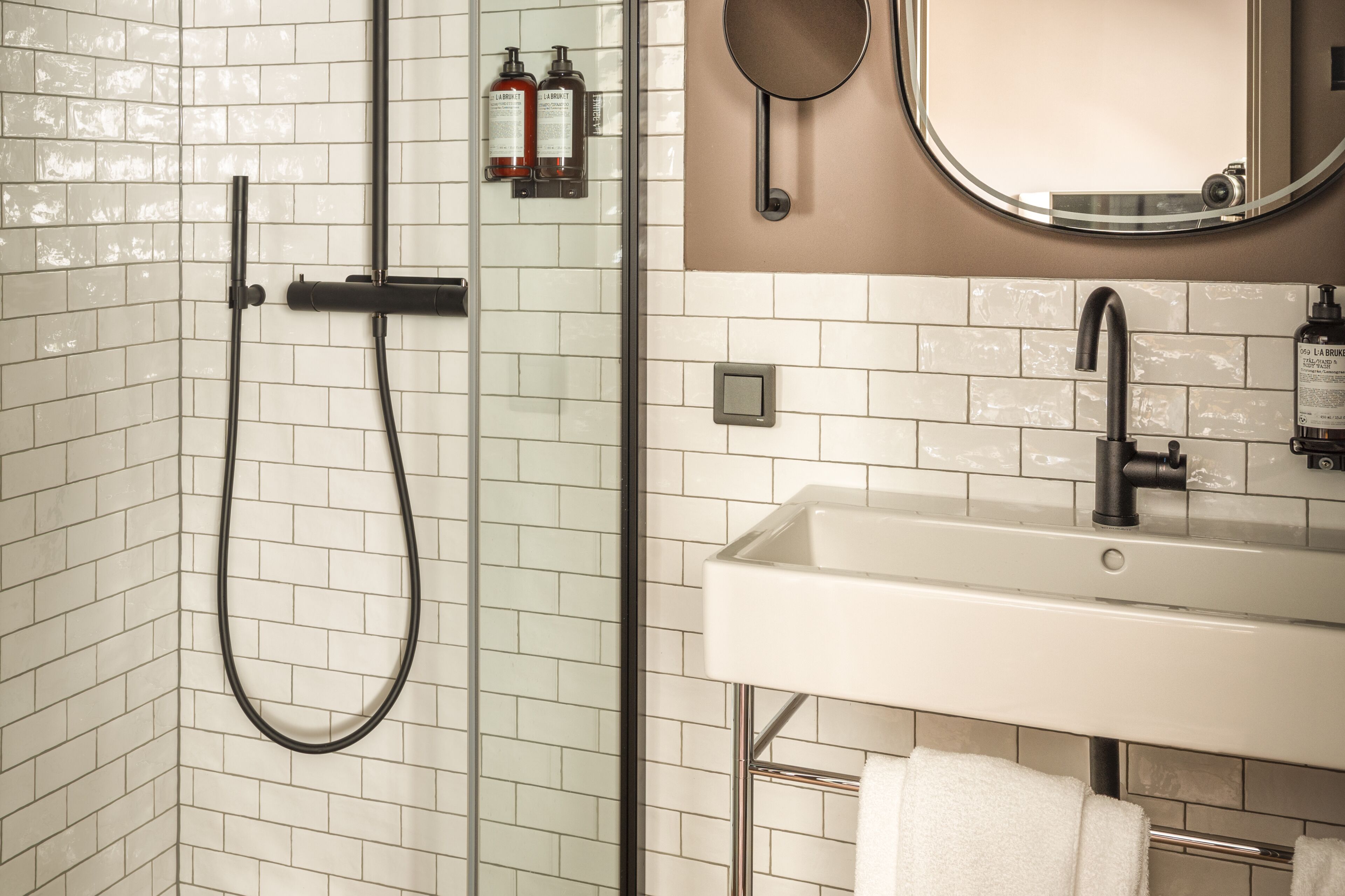 A bathroom with a glass-enclosed shower, a white sink, and a mirror.