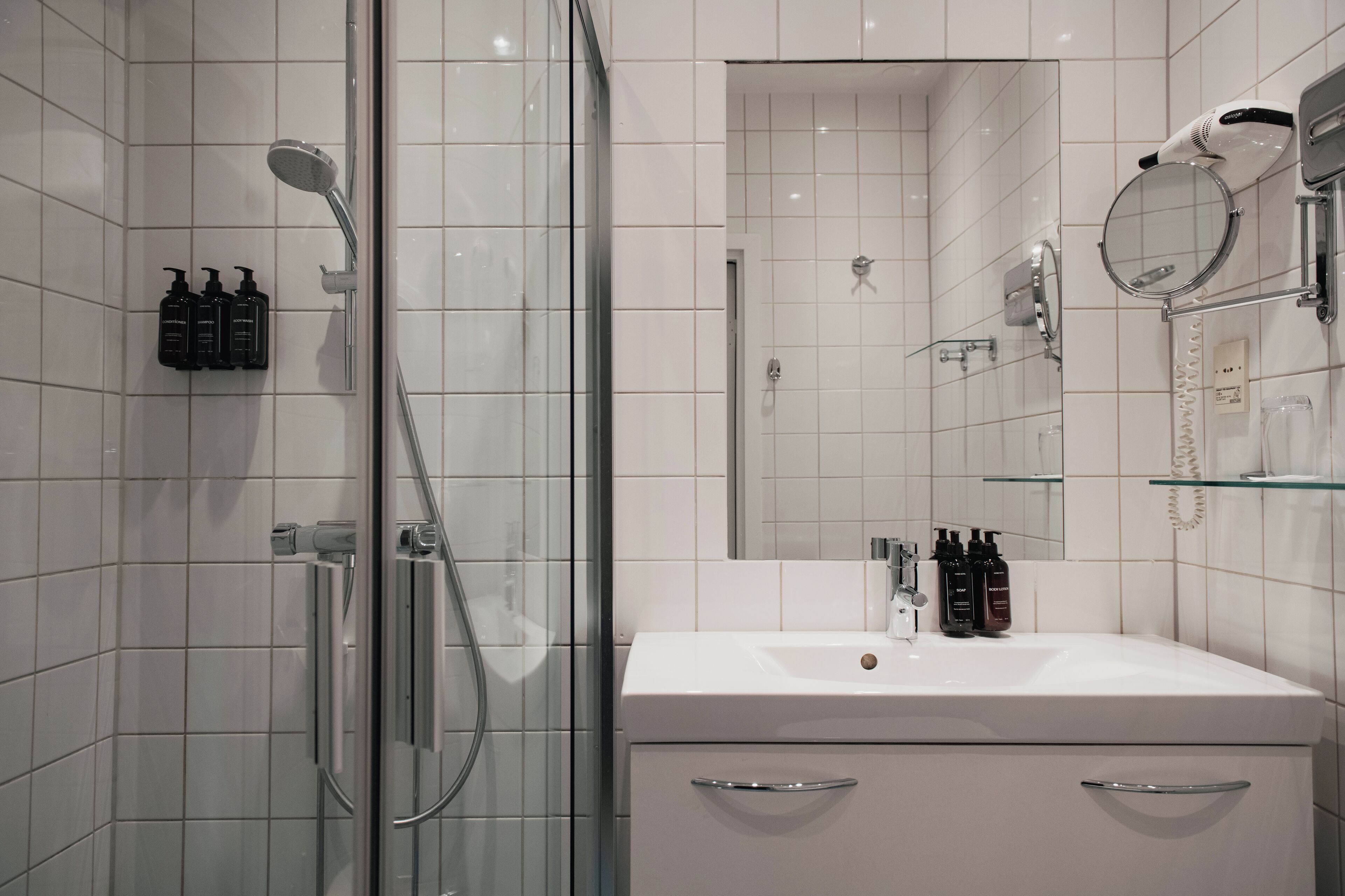 A modern bathroom with a glass shower enclosure, a white sink, and a mirror above it.