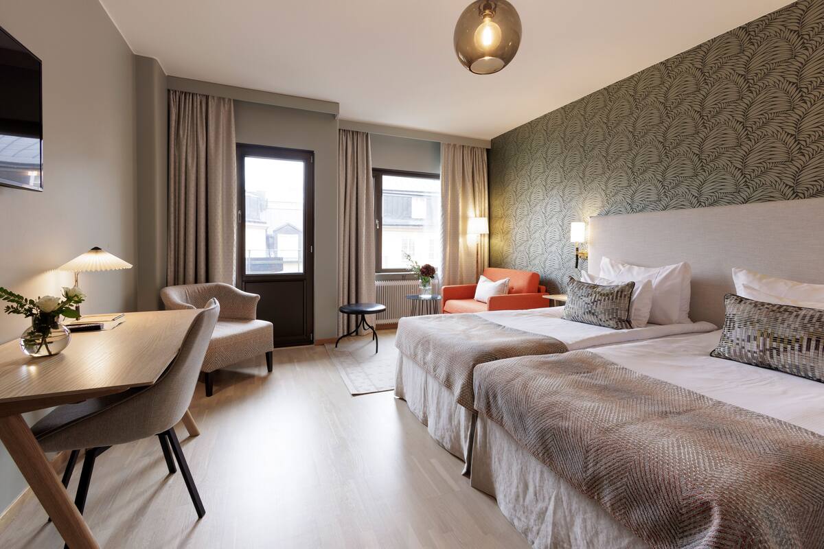 Una habitación de hotel con cama, escritorio, silla y una pequeña mesa.
