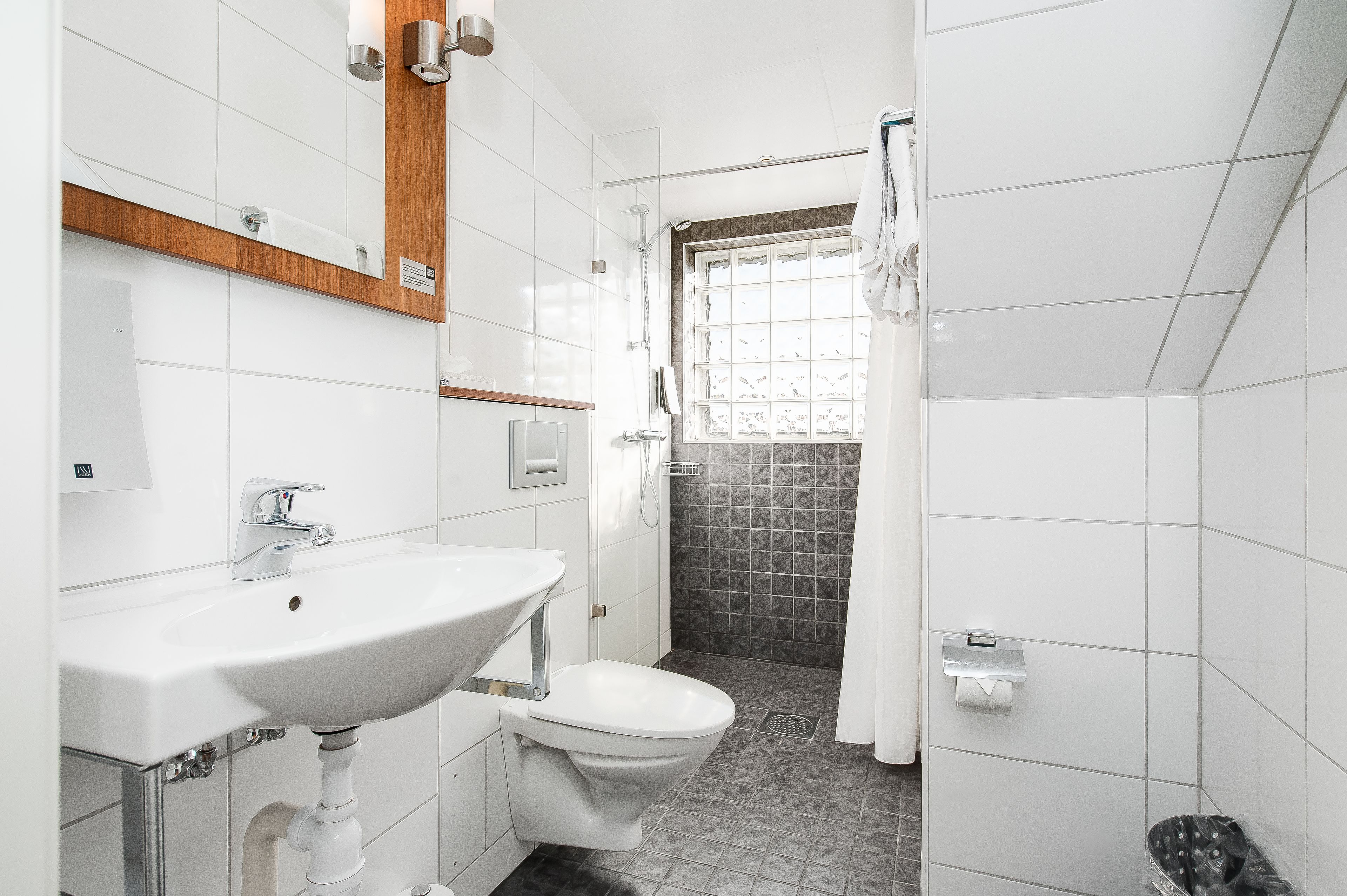 A modern bathroom with a white sink, a toilet, and a shower area.