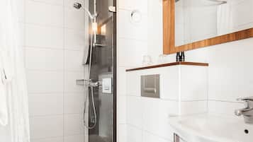 Ett modernt badrum med en dusch som är avskärmad med glasväggar, en vit toalett och ett handfat med en bänkskiva i trä.