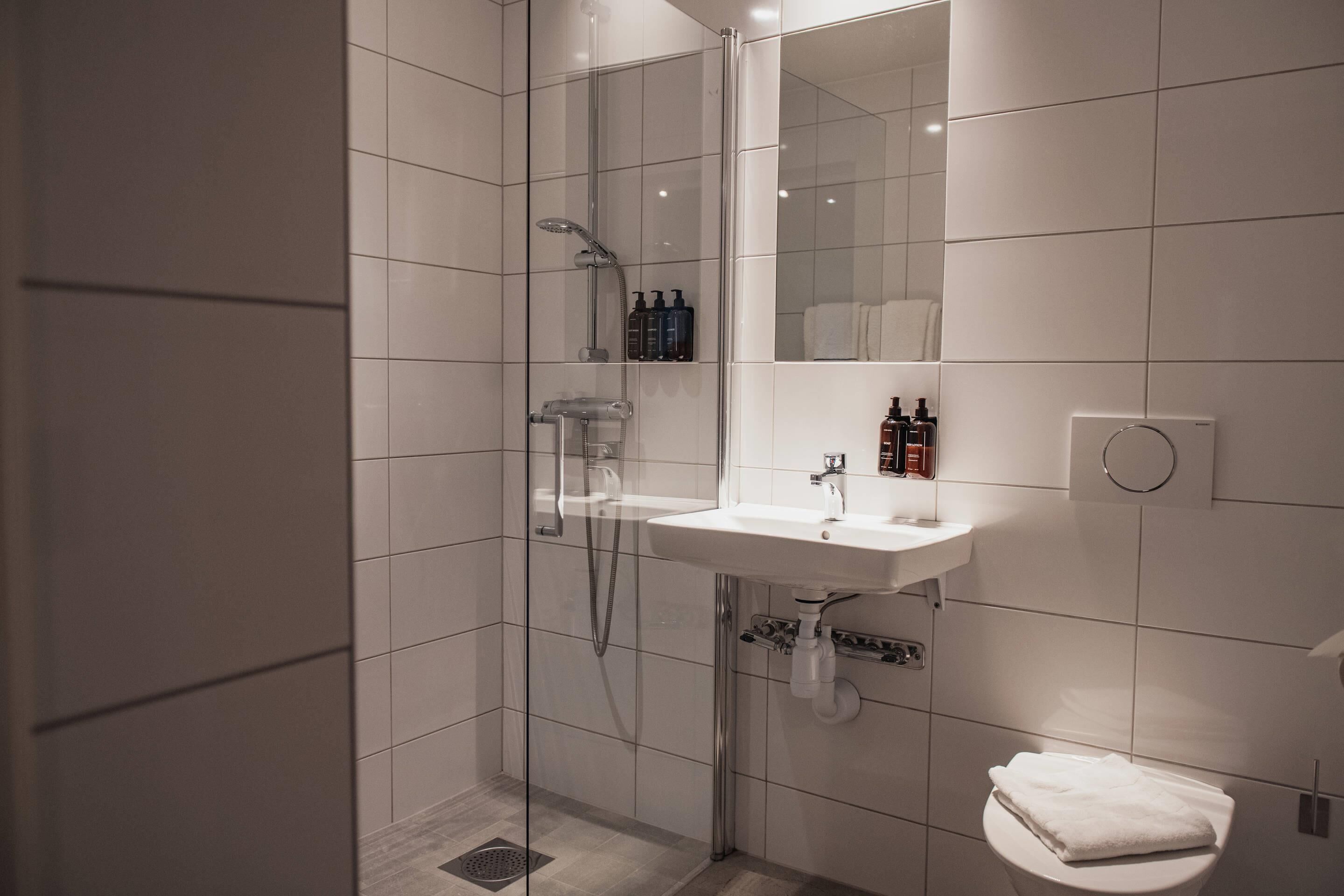 A modern bathroom with a glass-enclosed shower, a white sink, and a toilet.