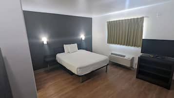 Quarto com cama, luminárias de cabeceira, janela com cortinas, aquecedor e um suporte para televisão.