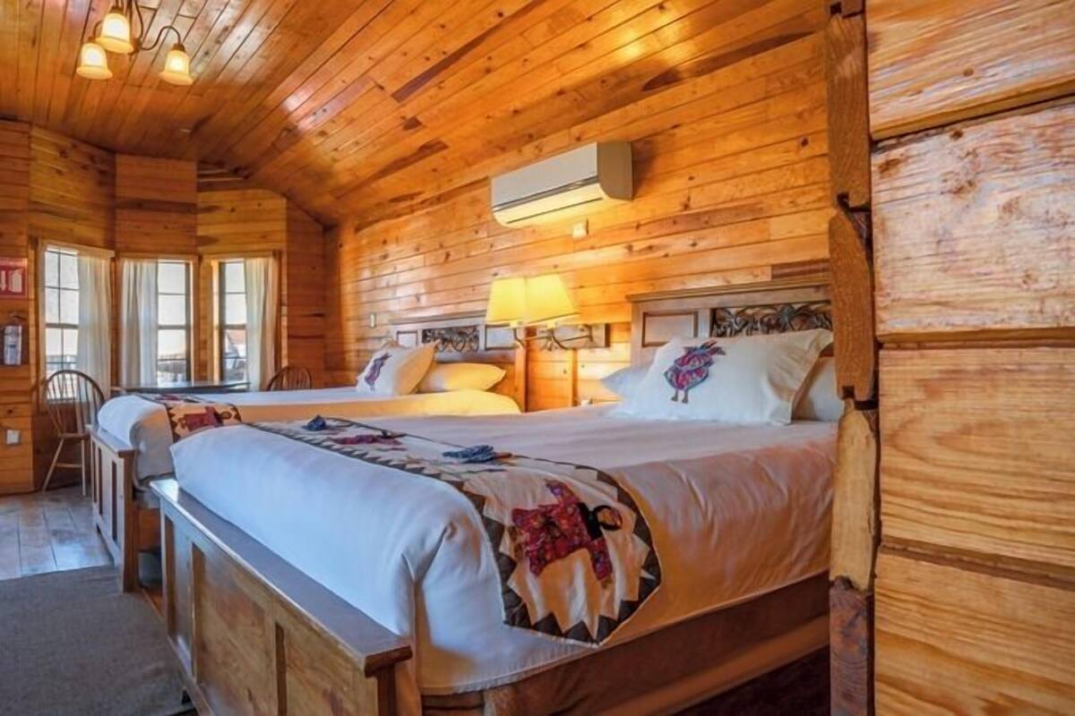 Une pièce aménagée comme un chalet en bois, avec deux lits, un bureau et une chaise.