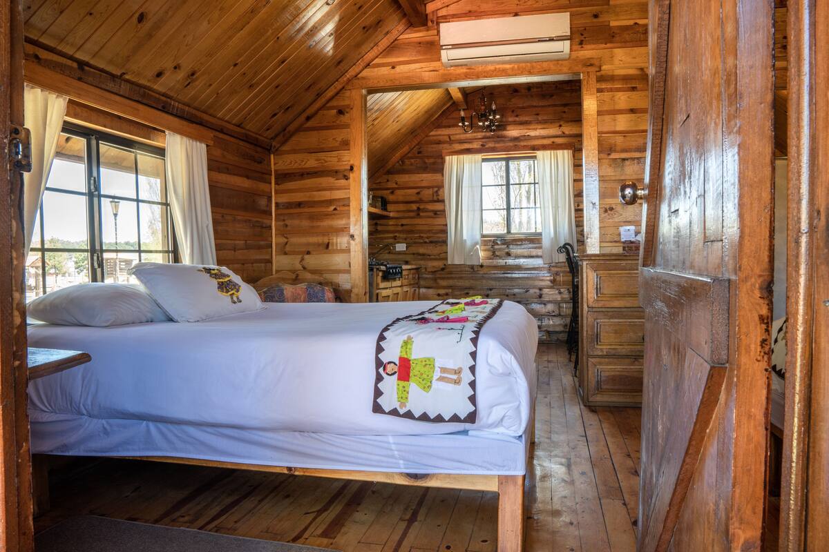 Une chambre dans une cabane en bois, avec un lit, une fenêtre et une petite kitchenette.