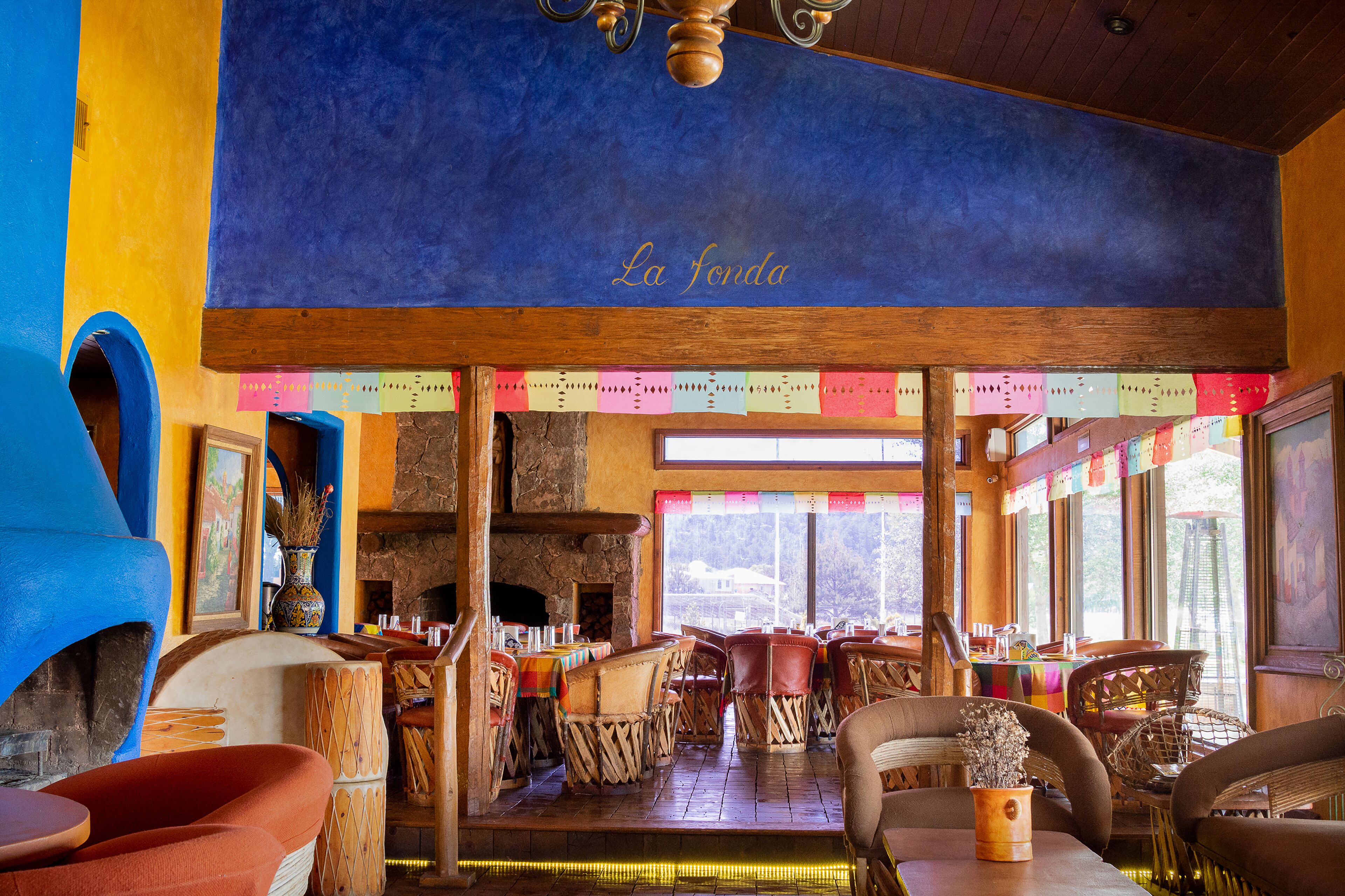 A restaurant interior with a stone fireplace, wooden ceiling, and colorful paper decorations.