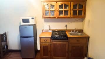 Une cuisine de taille réduite, dotée de meubles en bois, d’un four à micro-ondes, d’un réfrigérateur, d’une cuisinière et d’un évier.