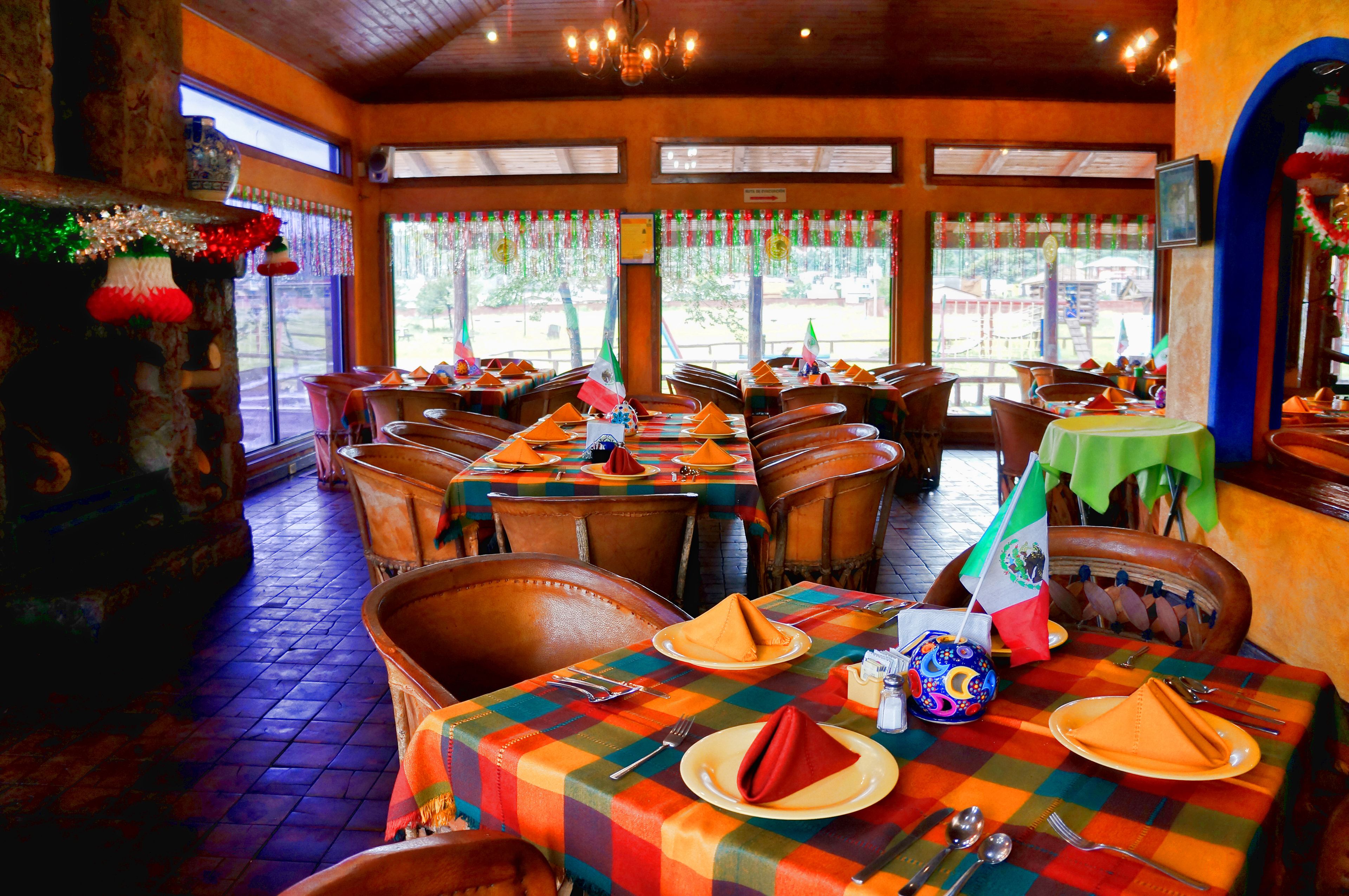 Un restaurante con mesas dispuestas para comer, sillas y una bandera en la mesa.