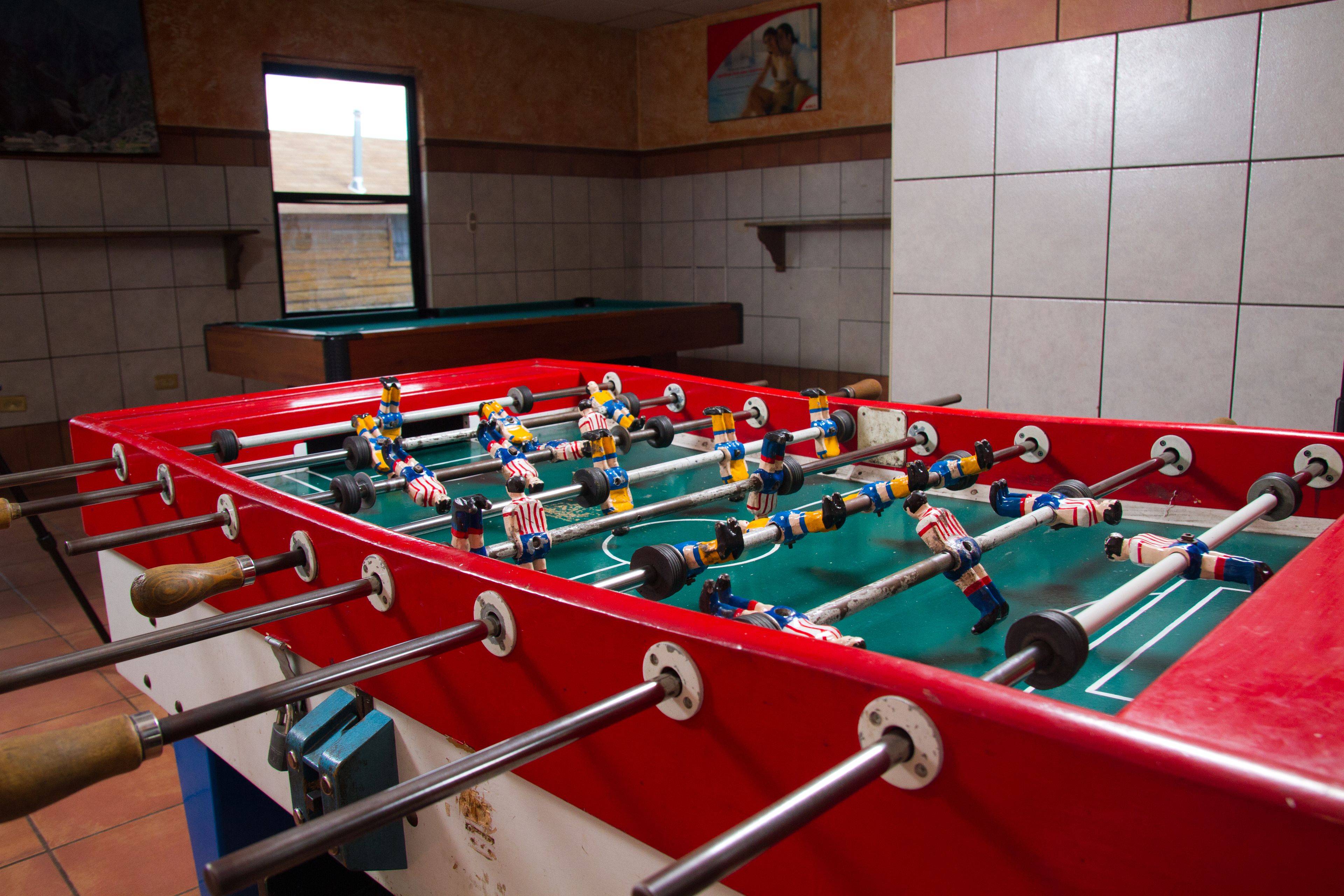 A foosball table with American flag-themed figures in a room with tiled walls and a window.