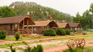 Eine rustikale Holzhütte mit Veranda, umgeben von einem roten Weg und einem Holzwagen.
