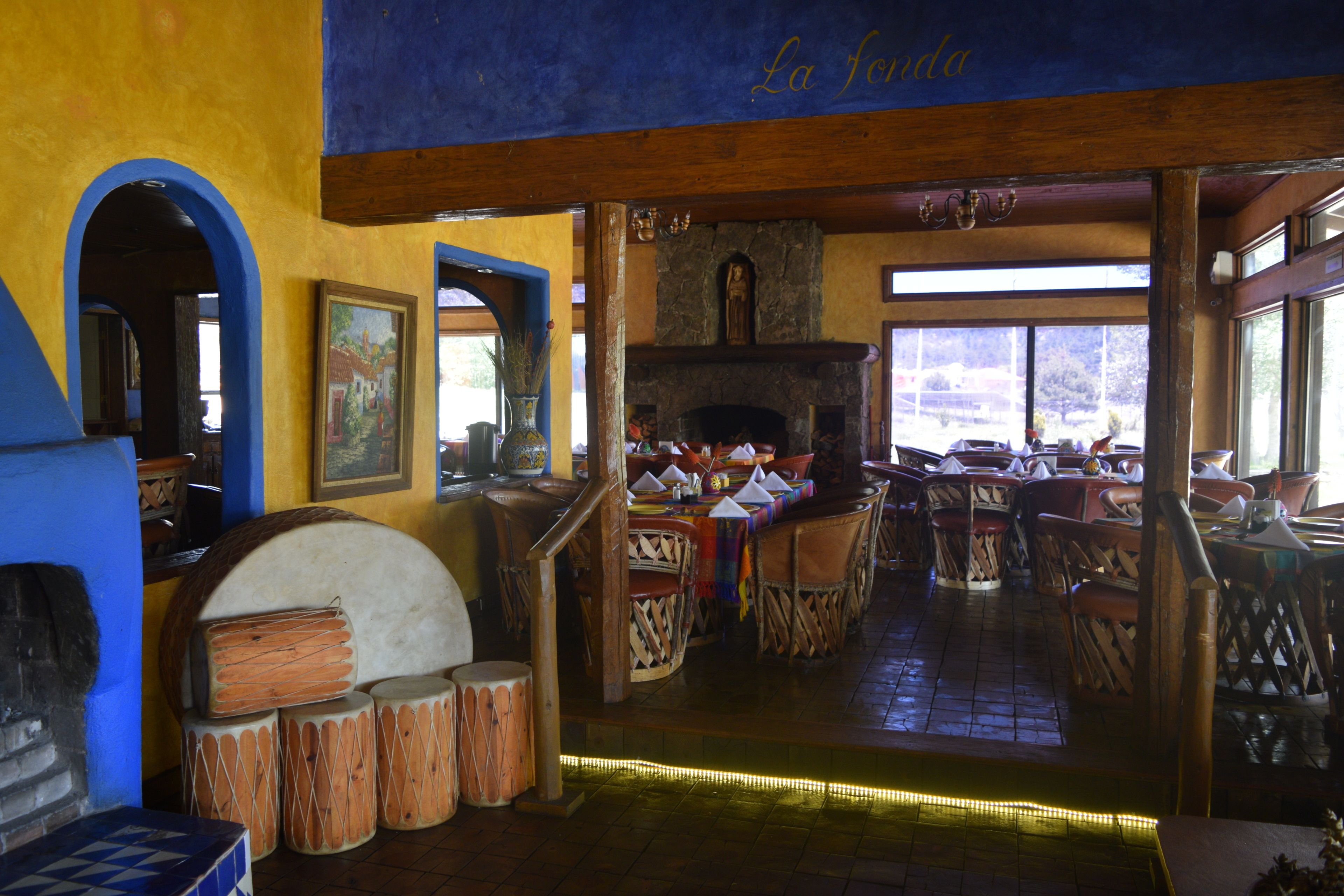 Un restaurante con decoración rústica, que incluye muebles de madera, una chimenea de piedra y vistas al exterior.