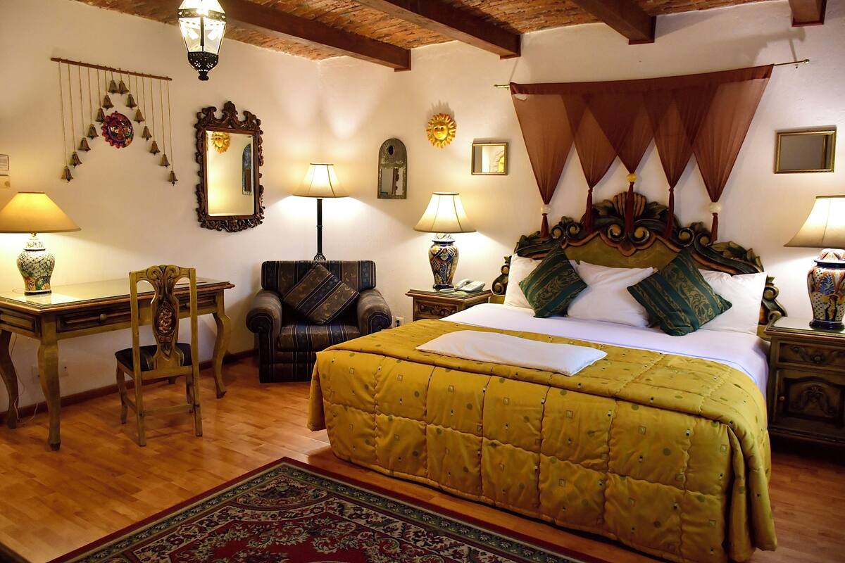Una camera tradizionale con un letto, due poltrone, una scrivania e un comodino.