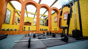 Ein Fitnessstudio mit Gewichthebern, Spiegeln und gelben Wänden.