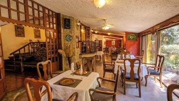 Zona pranzo con sedie e tavoli di legno, una scala e vista panoramica attraverso ampie finestre.
