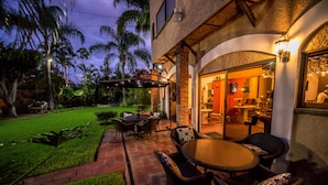 An outdoor patio with a round table and chairs, a brick pathway, and a well-maintained lawn. - La Mansiรณn del Sol (Zapopan)