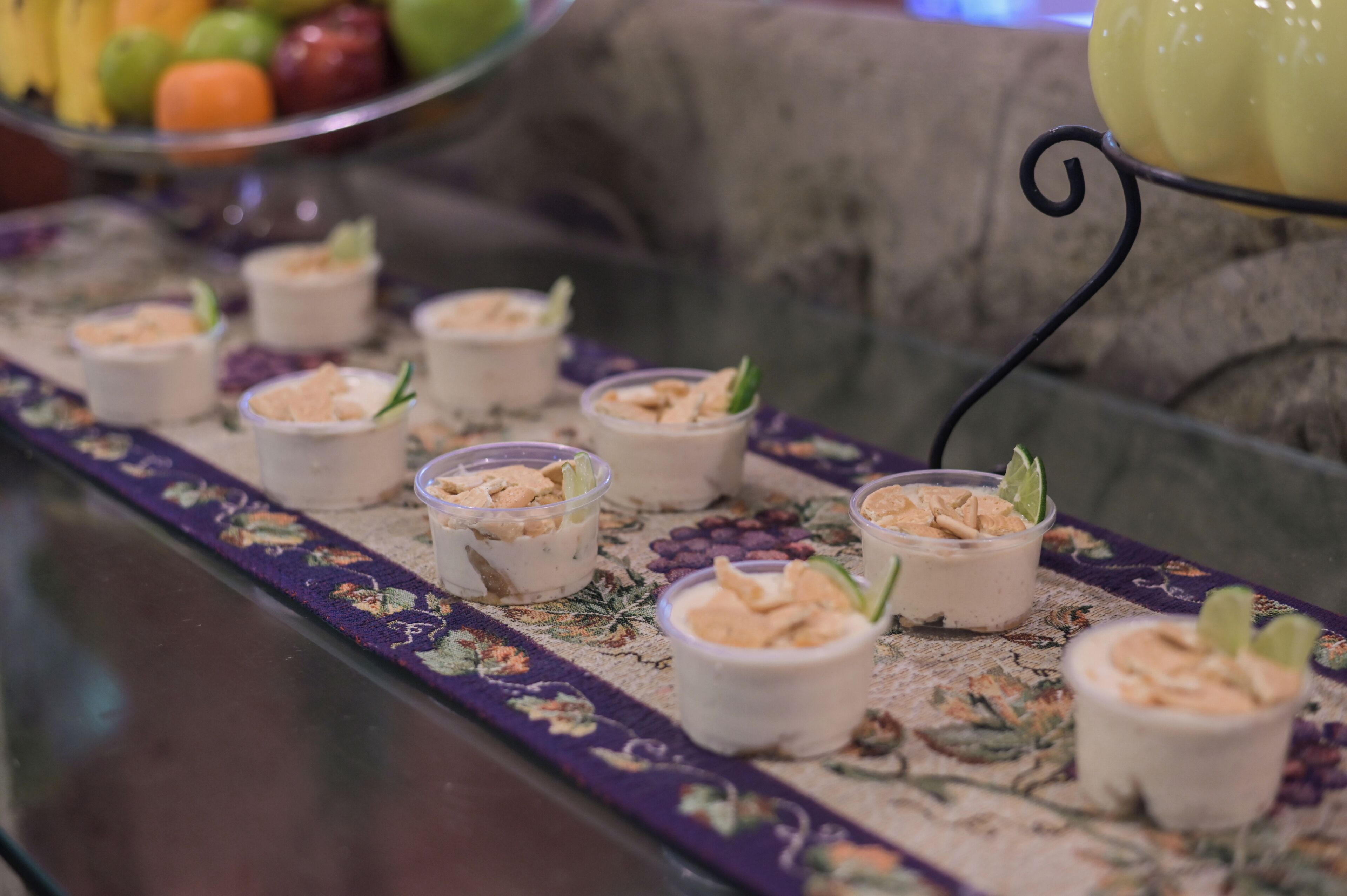 A buffet table with small dessert cups arranged in a row, each topped with a garnish.
