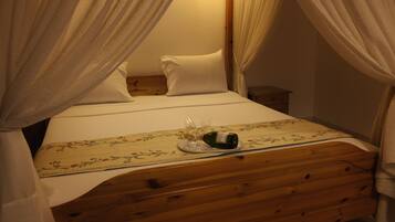 A bed with a wooden headboard, white bedding, and a floral-patterned tablecloth.