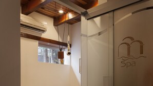 Una habitación con una cama, un puerta corrediza de vidrio y el logotipo de un spa, además de un equipo de aire acondicionado.