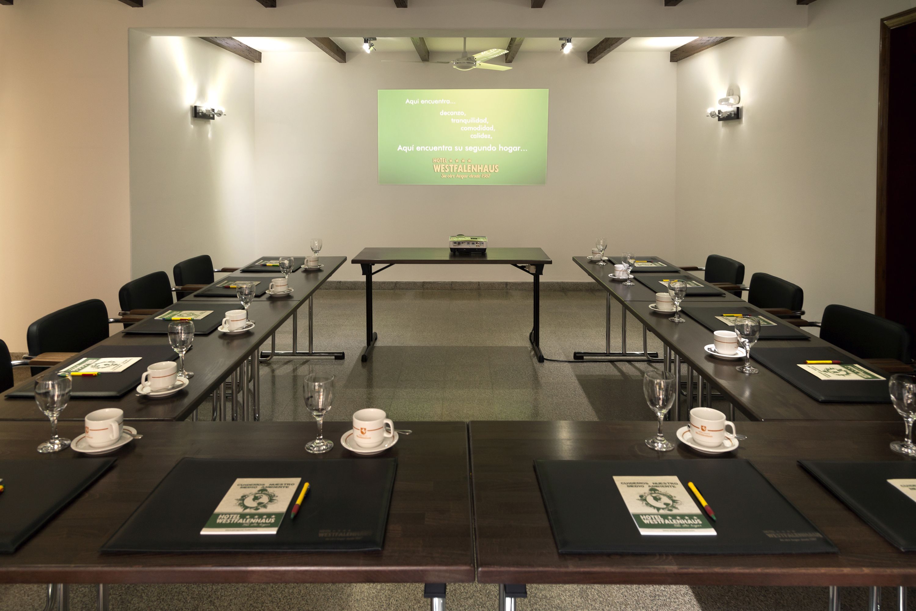 A conference room with a long table, chairs, and a presentation screen.