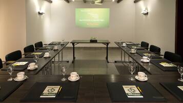 A conference room with a long table, chairs, and a presentation screen.