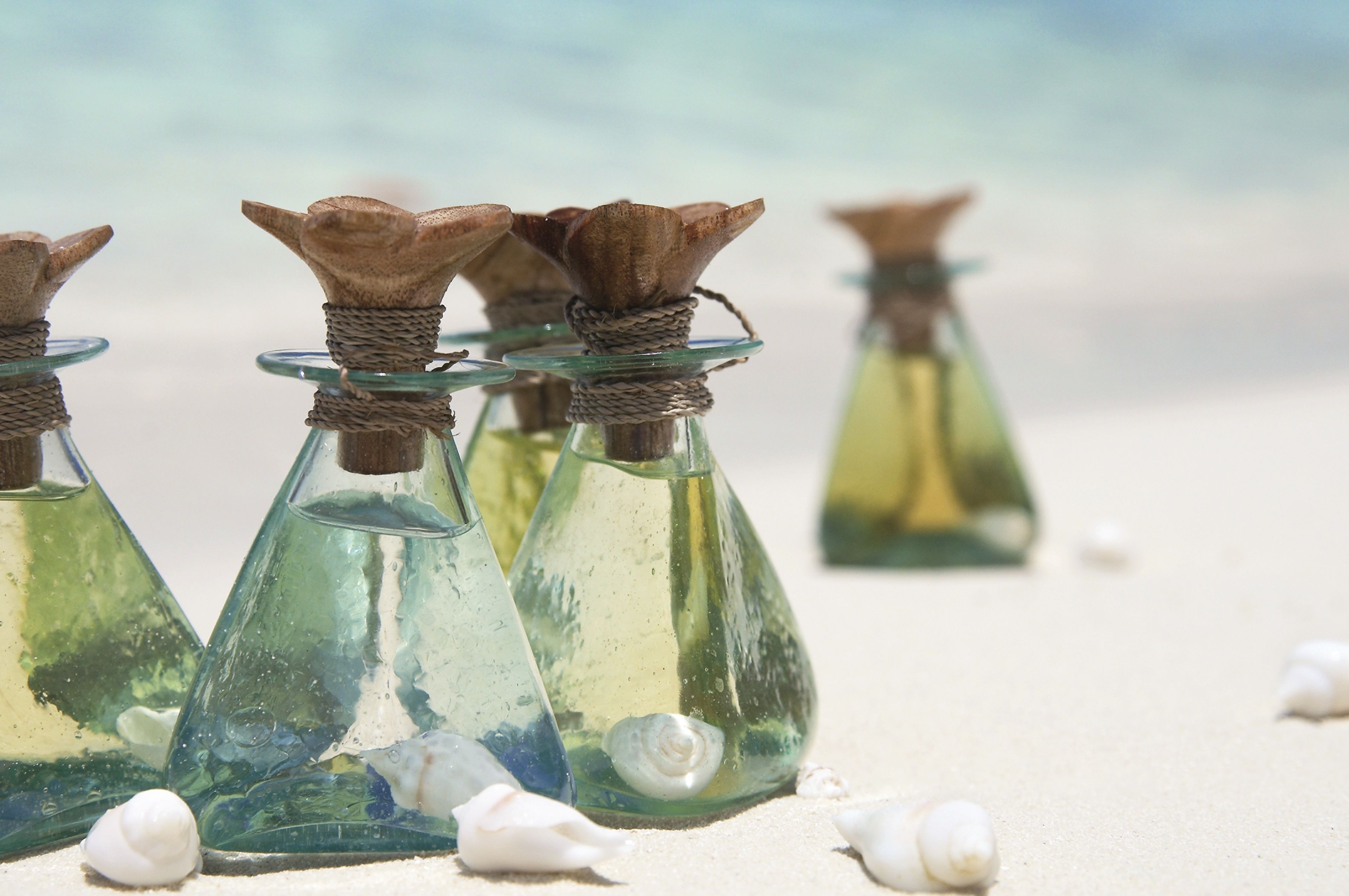 Glass bottles with brown tops on a sandy surface.