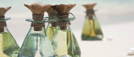 Glass bottles with brown tops on a sandy surface.