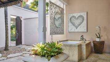 A bathroom with a bathtub, a sink, and a potted plant.