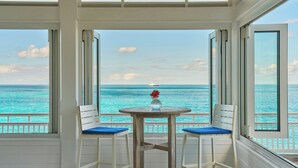 Una stanza con vista sull'oceano, un tavolo con un vaso e due sedie.
