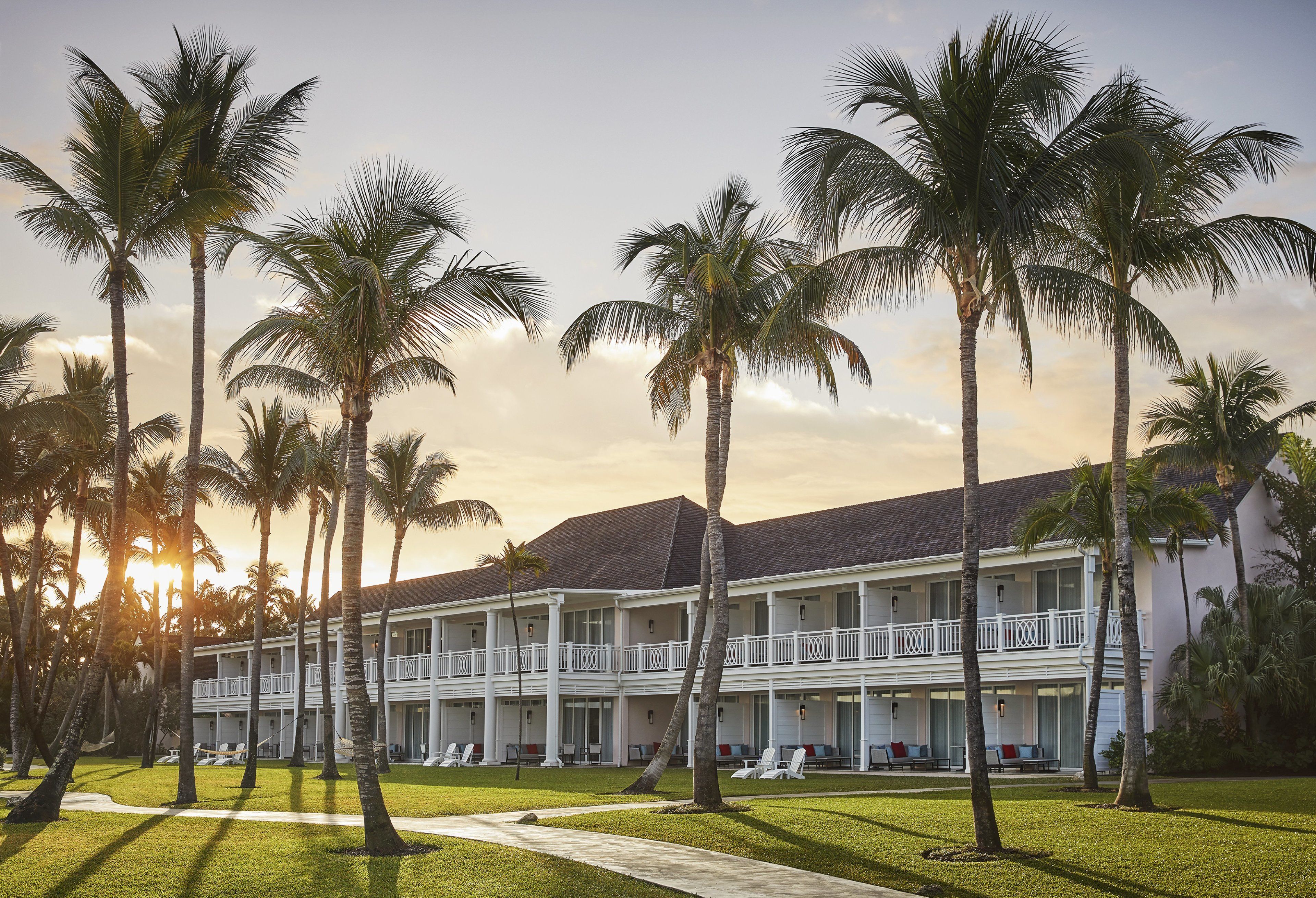 Ein Resort mit mehrstöckigen Gebäuden, Palmen und einem gepflegten Rasen.