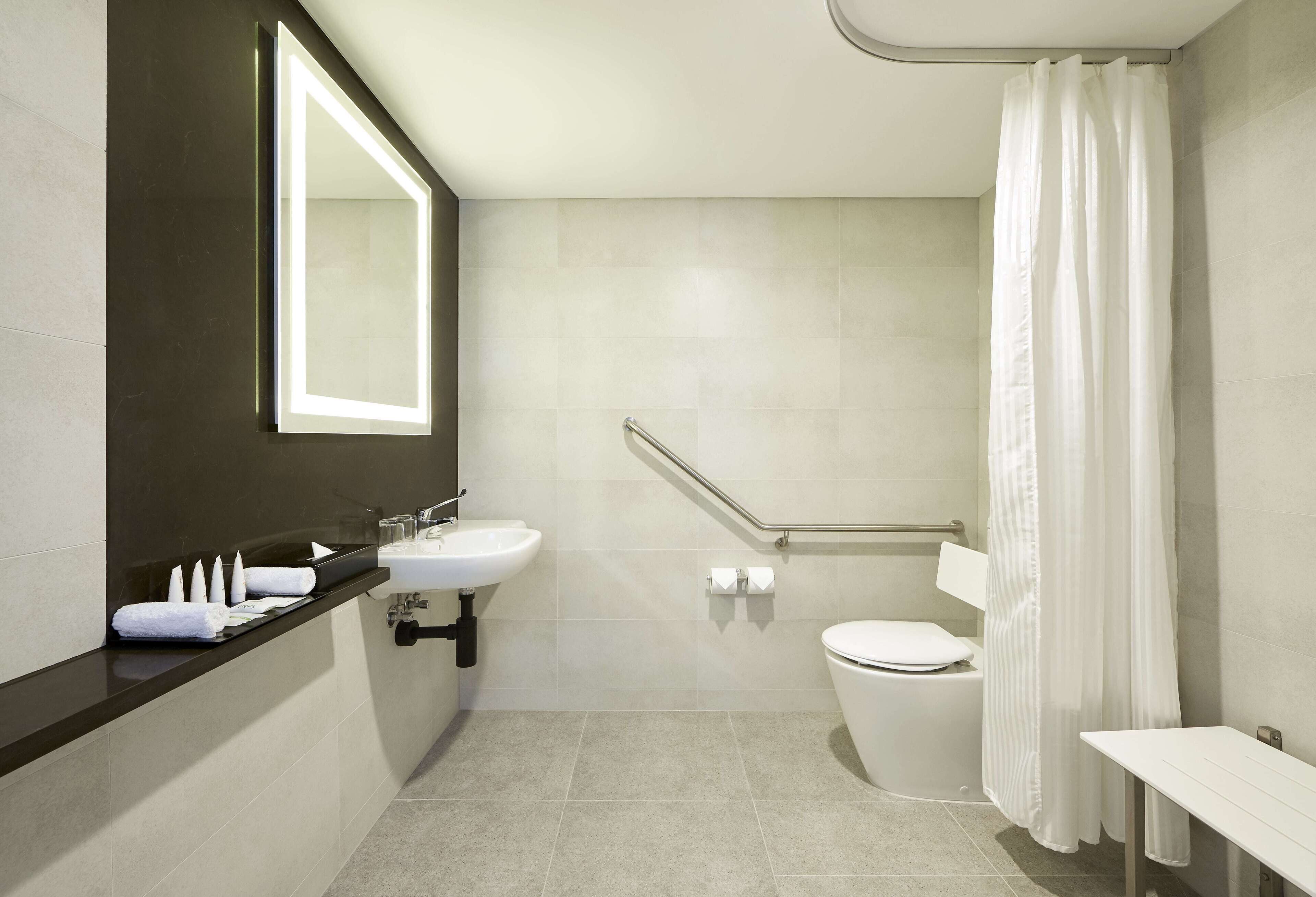 Et moderne badeværelse med håndvask, toilet og brusebad.