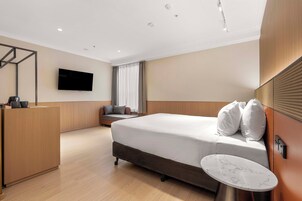 Une chambre d’hôtel moderne équipée d’un lit, d’un bureau, d’une télévision et d’une petite table.