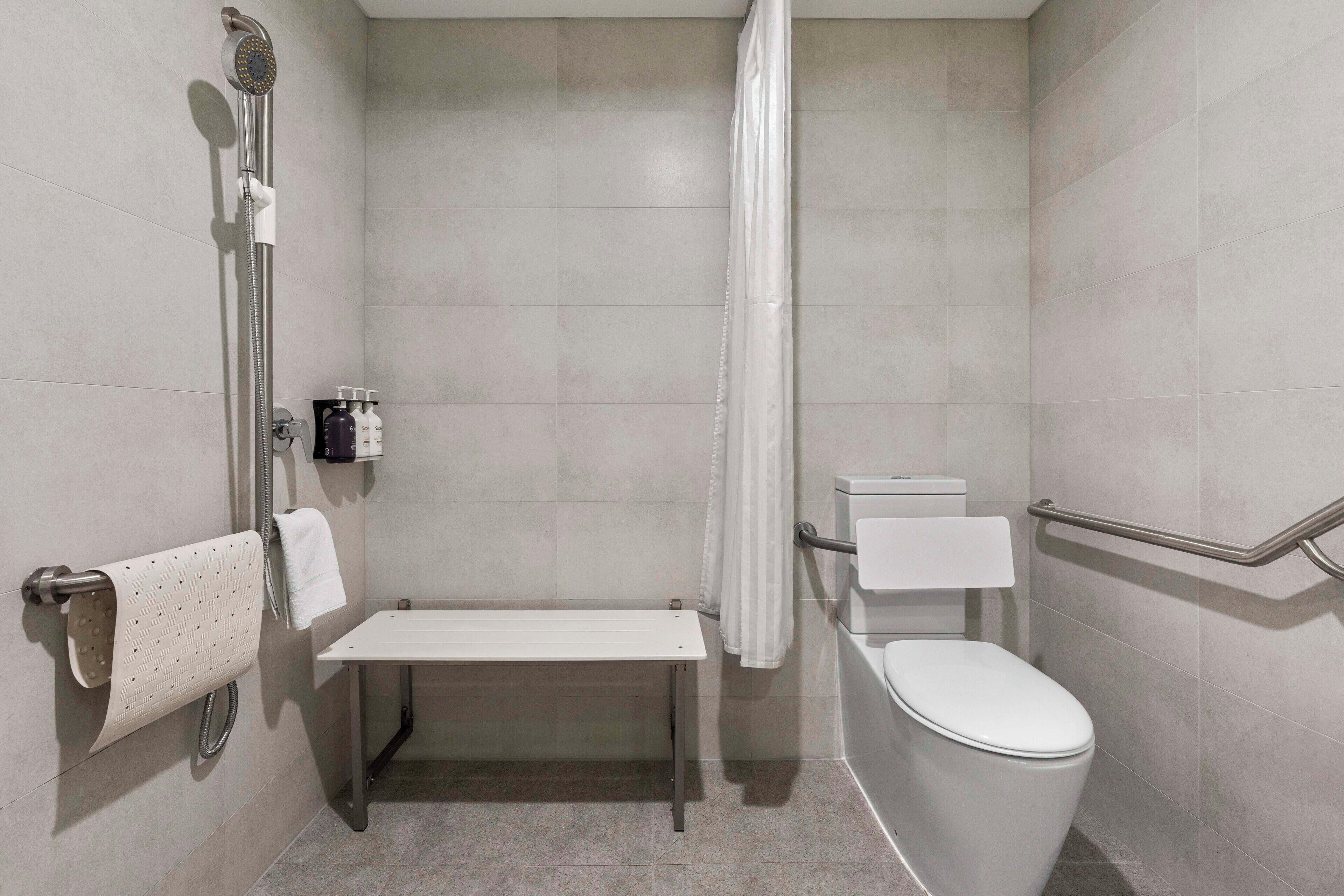 Ein modernes Badezimmer mit Dusche, Toilette und Sitzbank.