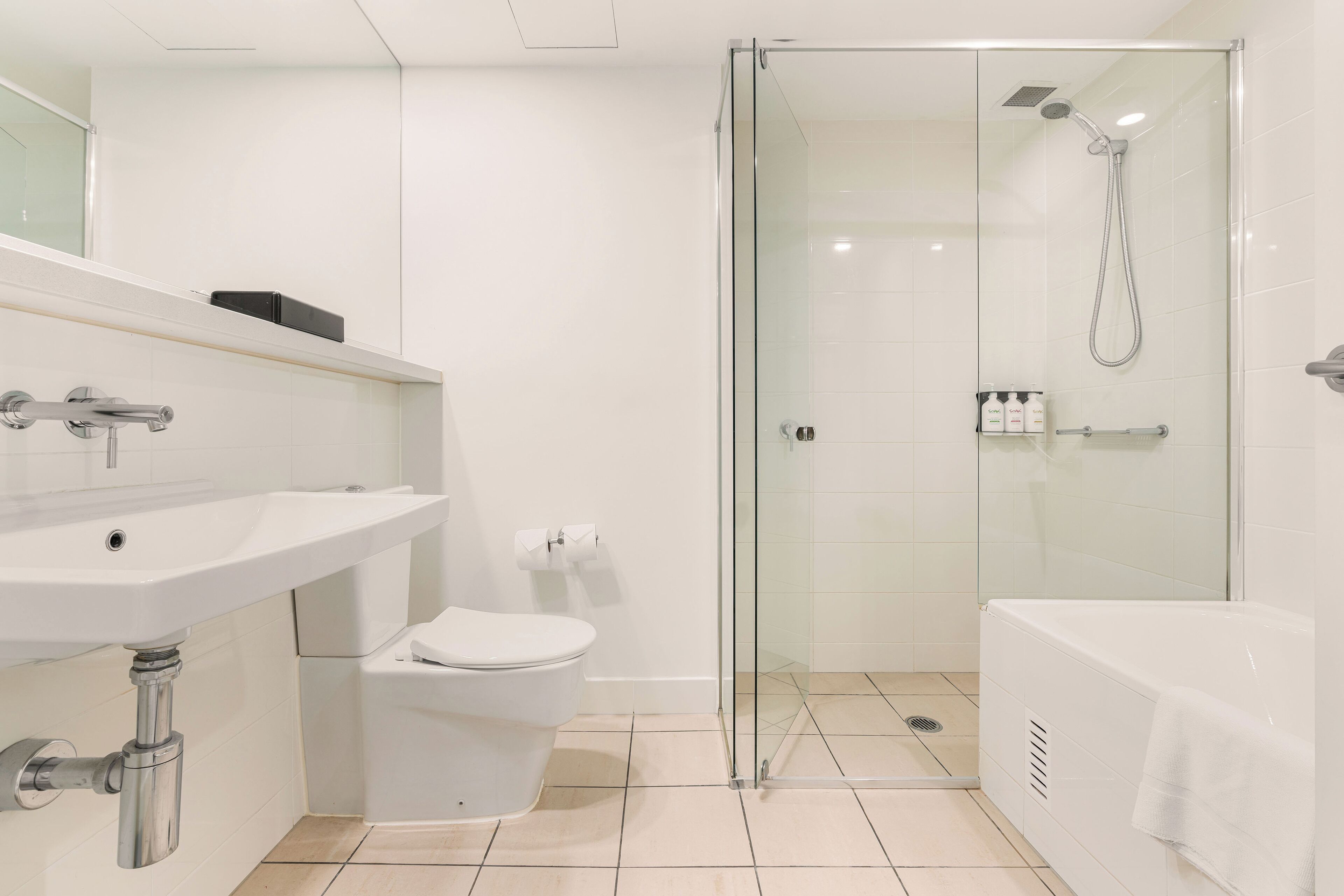 A modern bathroom with a glass-enclosed shower, a white sink, and a toilet.